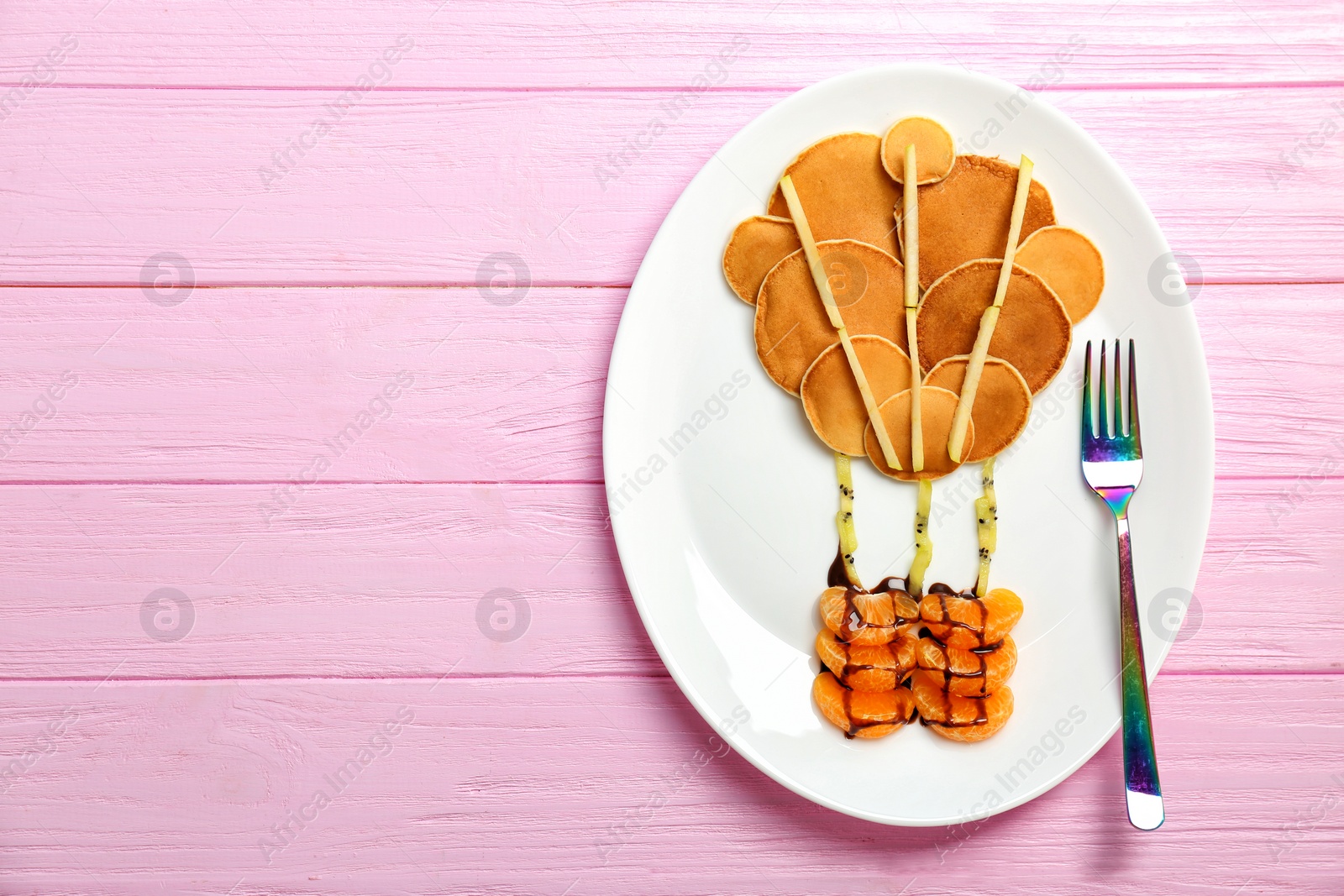 Photo of Plate with pancakes in form of hot air balloon on wooden background. Creative breakfast ideas for kids
