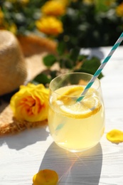 Photo of Composition with glass of refreshing lemonade and beautiful rose on white wooden table