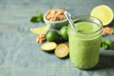 Photo of Fresh feijoa smoothie in glass on wooden table, closeup. Space for text