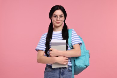 Student with books and backpack on pink background