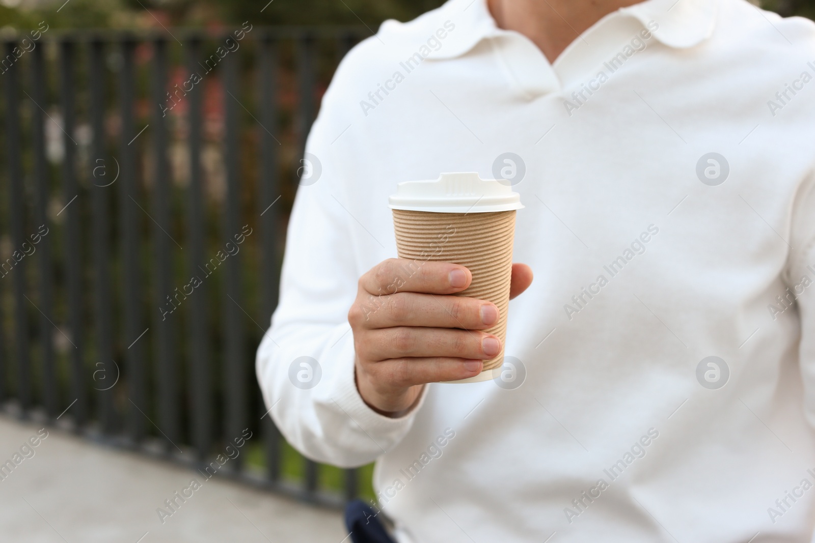 Photo of Coffee to go. Man with paper cup of drink outdoors, closeup
