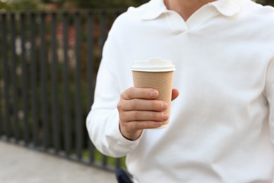 Coffee to go. Man with paper cup of drink outdoors, closeup