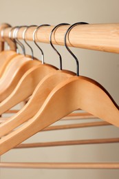 Photo of Clothes hangers on wooden rack against beige background, closeup