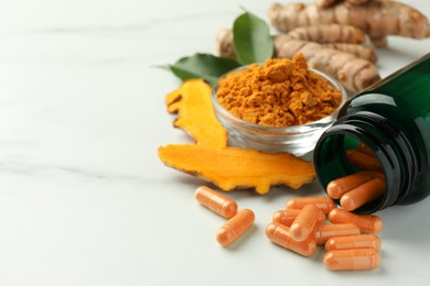 Photo of Aromatic turmeric powder, pills and raw roots on white marble table, closeup. Space for text