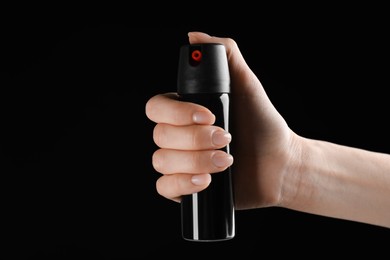 Woman holding pepper spray on black background, closeup. Space for text