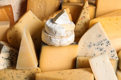 Different types of delicious cheese as background, closeup