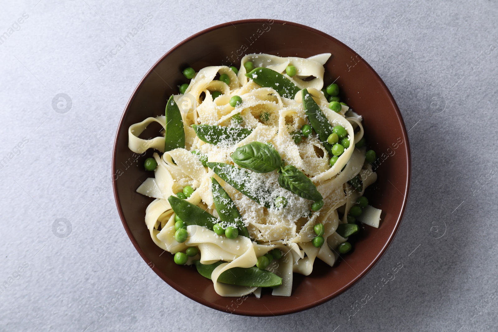 Photo of Delicious pasta with green peas and cheese on grey table, top view