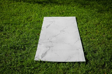 Photo of Karemat or fitness mat on green grass outdoors