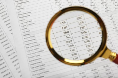 Photo of Looking on accounting documents through magnifying glass, closeup. Space for text