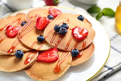 Photo of Delicious pancakes with fresh berries and syrup on table, closeup