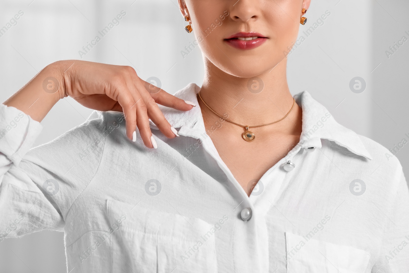 Photo of Beautiful woman with elegant jewelry on light background, closeup