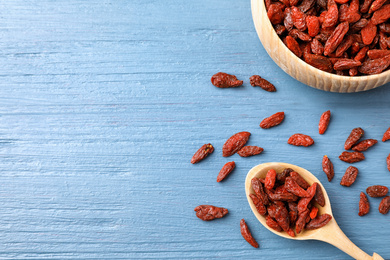 Photo of Dried goji berries on blue wooden table, flat lay. Space for text