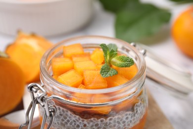 Photo of Delicious dessert with persimmon and chia seeds in jar, closeup