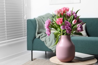 Photo of Beautiful bouquet of colorful tulip flowers on coffee table in room, space for text