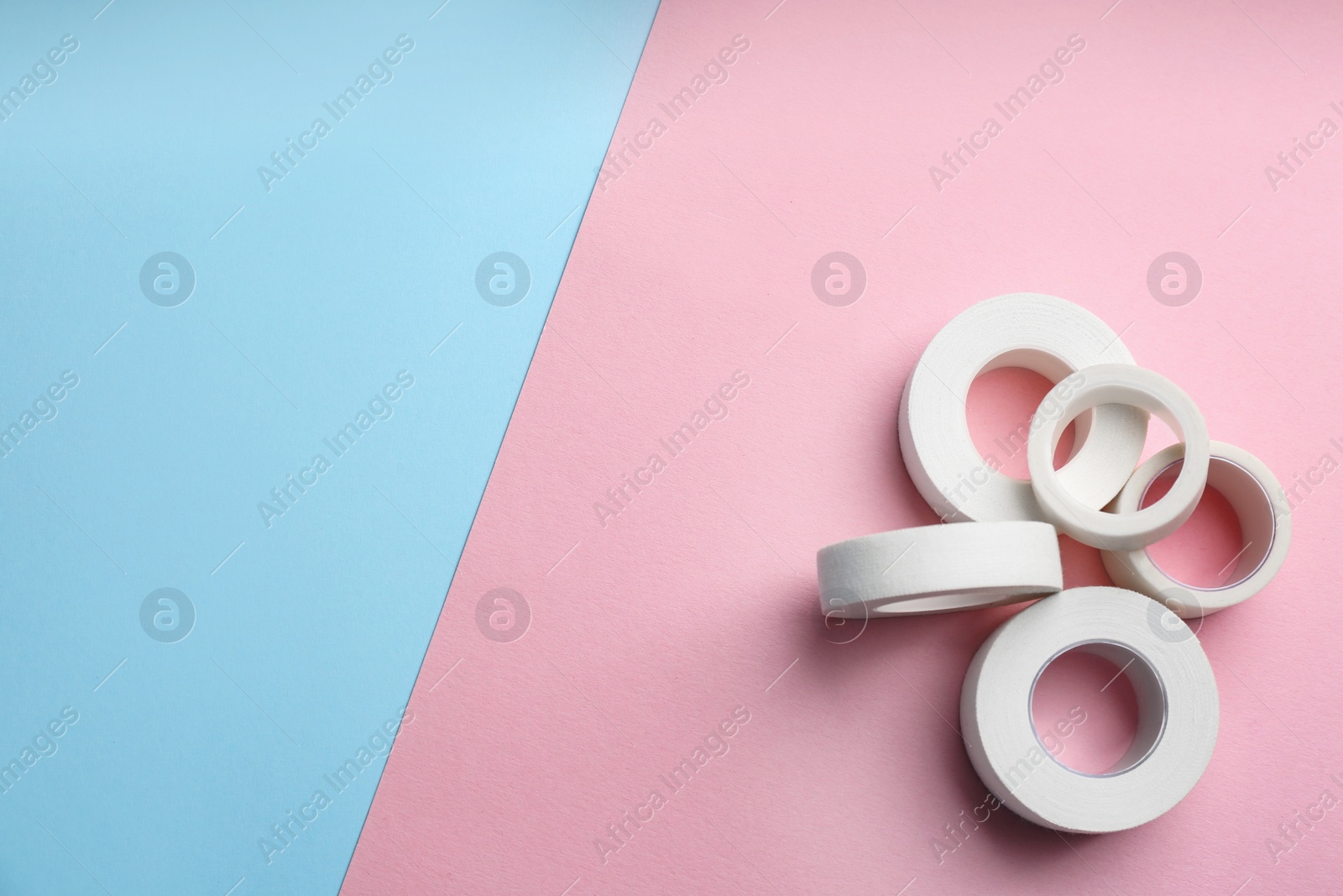 Photo of Sticking plaster rolls on color background, flat lay. Space for text