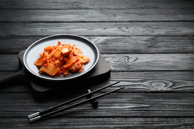 Delicious kimchi with Chinese cabbage served on black wooden table. Space for text