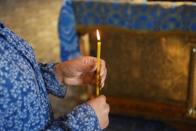 Photo of Mature woman holding candle in church, closeup