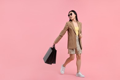 Photo of Beautiful woman with shopping bags on pink background. Space for text