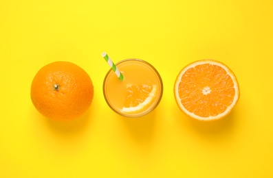 Photo of Glass of orange juice and fresh fruits on yellow background, flat lay