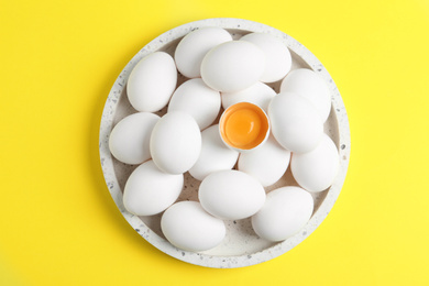 Photo of Fresh raw chicken eggs on yellow background, top view