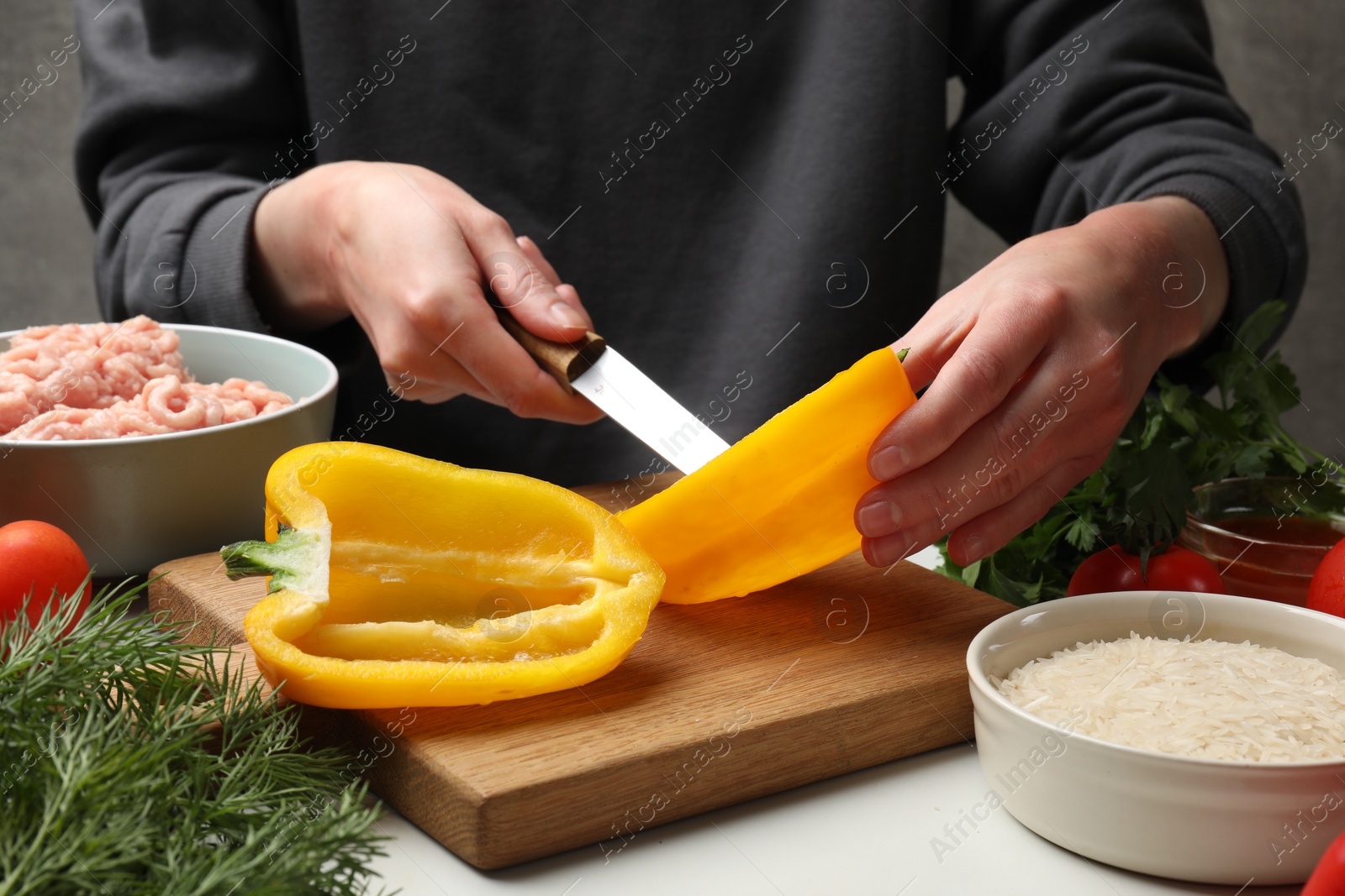 Photo of Woman making stuffed peppers with ground meat at white table, closeup