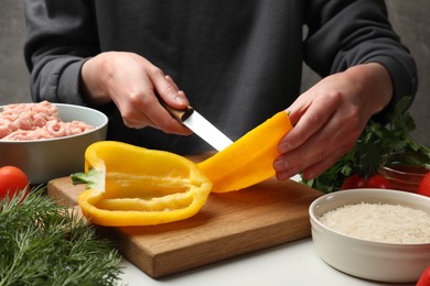 Woman making stuffed peppers with ground meat at white table, closeup