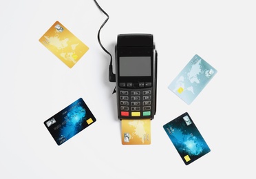 Photo of Modern payment terminal and credit cards on white background, top view