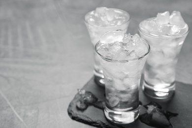 Shot glasses with vodka and ice on grey table. Space for text