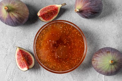 Photo of Glass bowl of tasty sweet jam and fresh figs on light table, flat lay