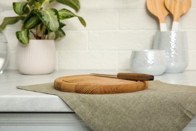 Photo of Clean towel, wooden cutting board and knife on countertop in kitchen