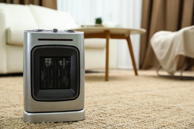 Photo of Modern electric fan heater on floor at home. Space for text