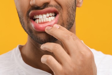 Photo of Man showing his healthy teeth and gums on orange background, closeup