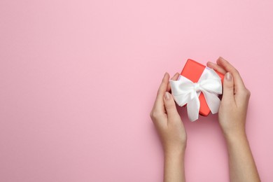 Woman holding beautiful gift box on pink background, top view. Space for text