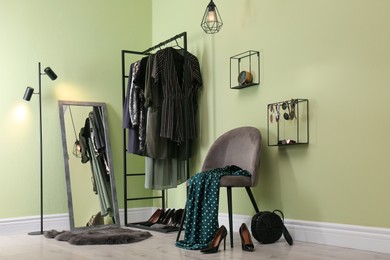 Modern dressing room interior with clothing rack, chair and mirror