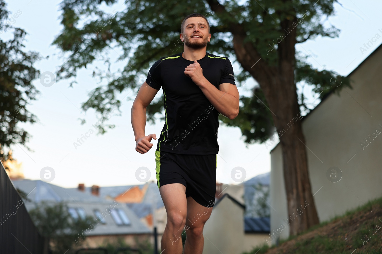 Photo of Attractive sporty man in fitness clothes jogging outdoors