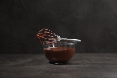 Bowl of chocolate cream and whisk on gray table