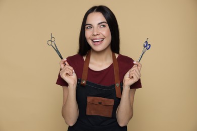 Photo of Portrait of happy hairdresser with professional scissors on beige background