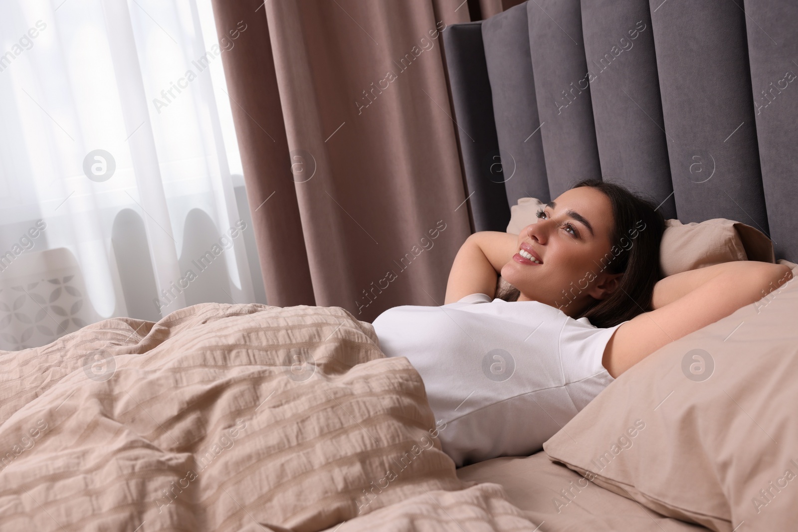 Photo of Happy woman in bed at home. Lazy morning