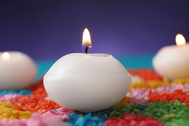 Photo of Diwali celebration. Burning candles and colorful rangoli against blurred background, closeup
