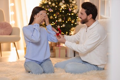 Photo of Making proposal. Man with engagement ring surprising his girlfriend at home on Christmas