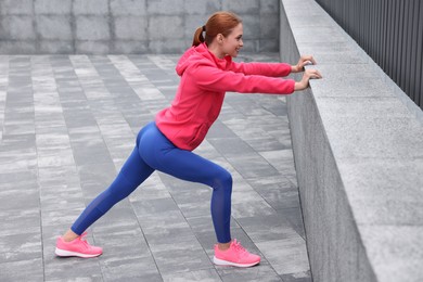 Beautiful woman in gym clothes doing exercises on street