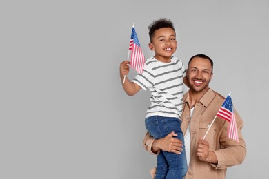 Photo of 4th of July - Independence Day of USA. Happy man and his son with American flags on light grey background, space for text