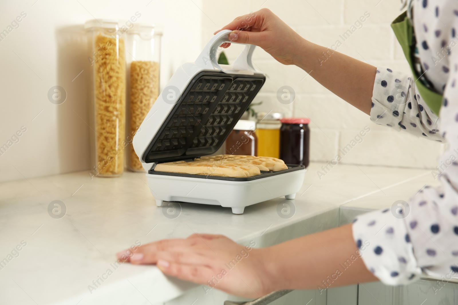 Photo of Woman making delicious Belgian waffles in kitchen, closeup