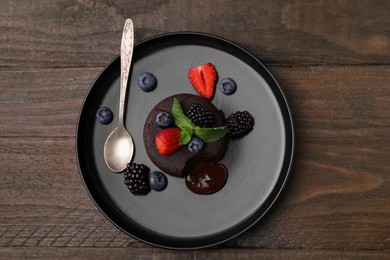 Photo of Plate with delicious chocolate fondant, berries and mint on wooden table, top view