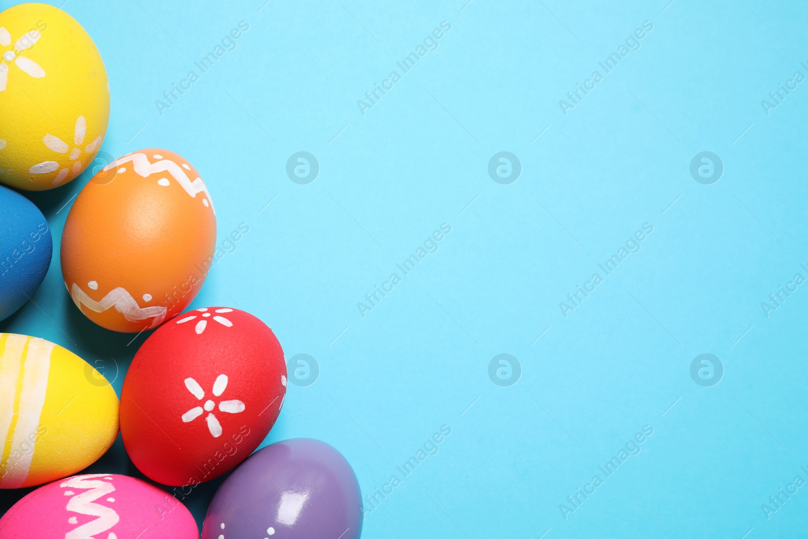 Photo of Colorful Easter eggs on light blue background, flat lay. Space for text