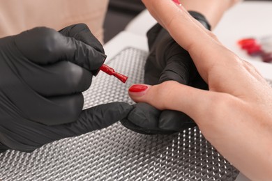 Professional manicurist working with client at table, closeup