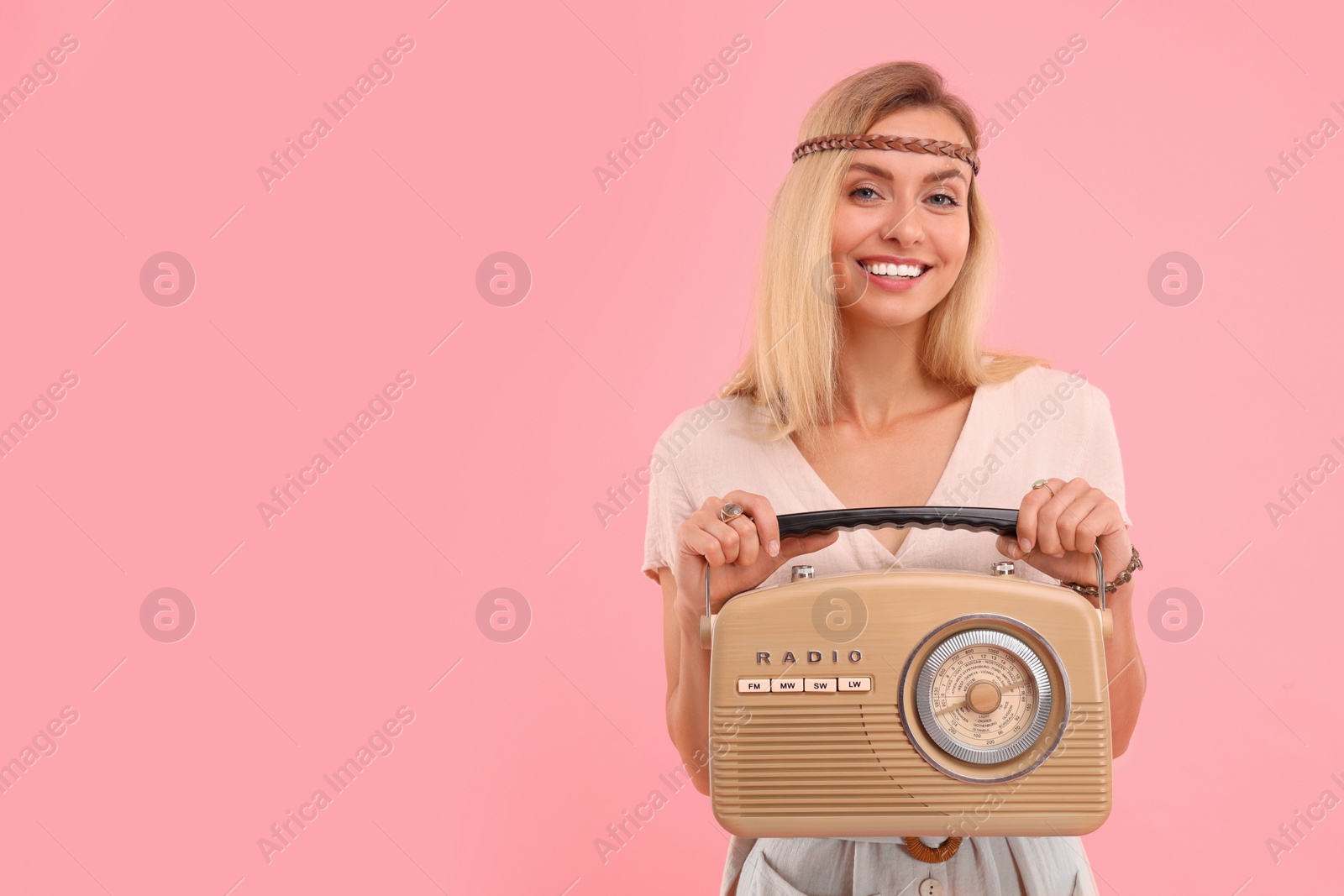 Photo of Portrait of happy hippie woman with retro radio receiver on pink background. Space for text