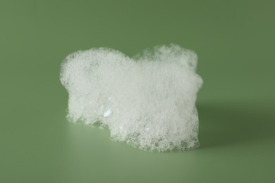 Photo of Drop of fluffy bath foam on olive background