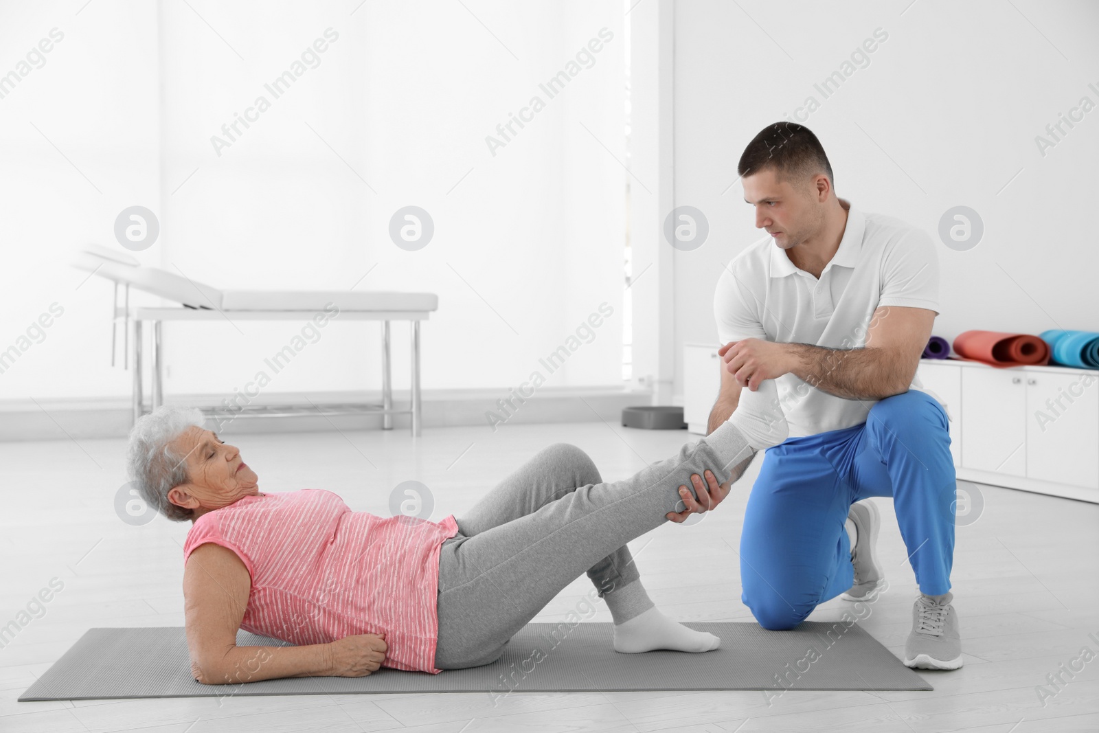 Photo of Professional physiotherapist working with elderly patient in rehabilitation center. Space for text