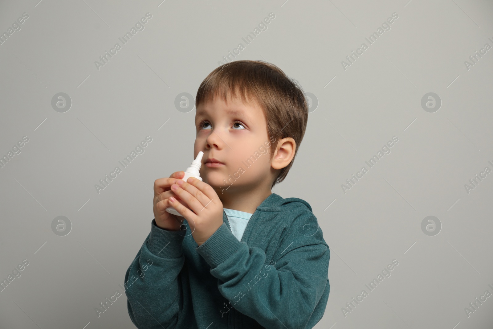 Photo of Little boy using nasal spray on light grey background